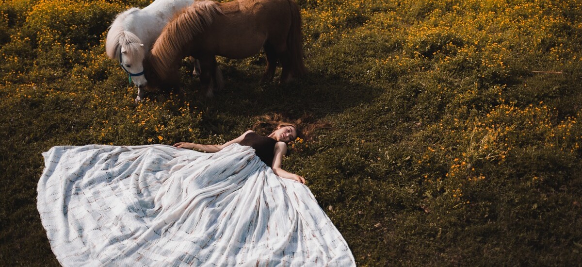 Bride in Abruzzo lying in the grass among ponys and horses looking like a fairytale